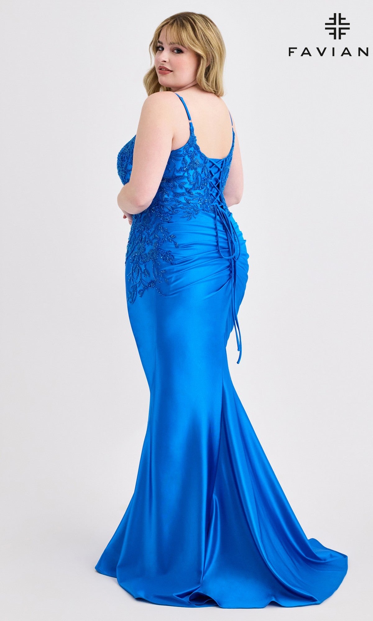 A woman in a bright blue, curve-hugging gown with a beaded lace bodice and mermaid silhouette poses gracefully. The